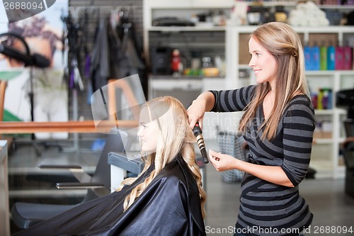 Image of Stylist Curling Womans Hair