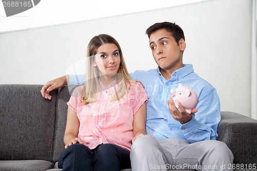 Image of Man Holding Piggybank While Sitting With Woman