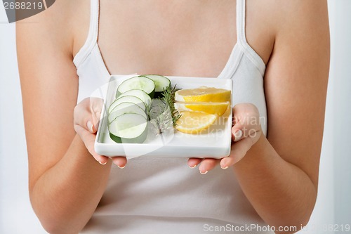 Image of Woman With Plate Of Sliced Cucumber And Lime