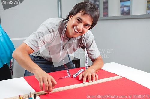 Image of Happy Dressmaker Measuring Red Fabric