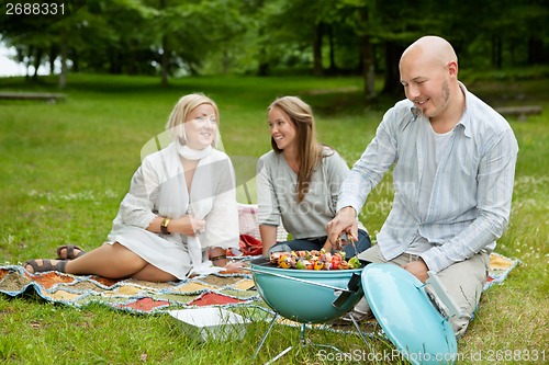 Image of Friends in Park Eating BBQ Picnic