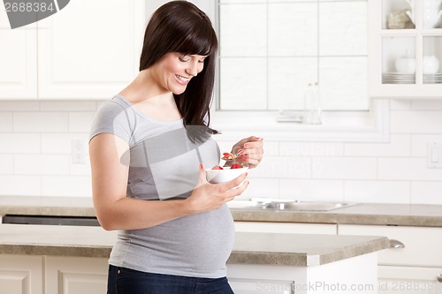Image of Pregnant Woman in Kitchen Eating Snack