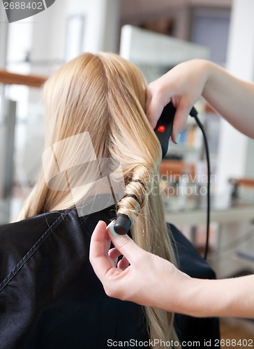 Image of Stylist Curling Womans Hair
