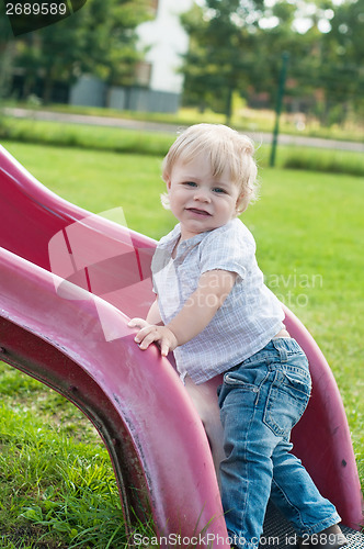 Image of Smiling child playing on a baby slide