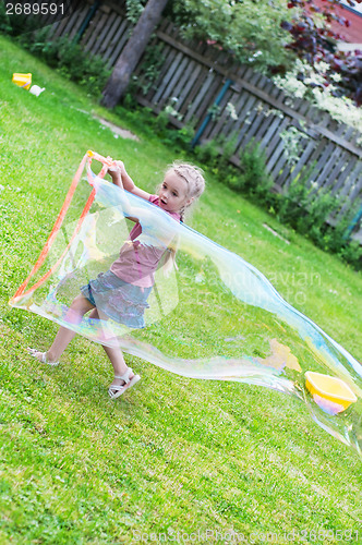 Image of Little girl making giant soap bubble