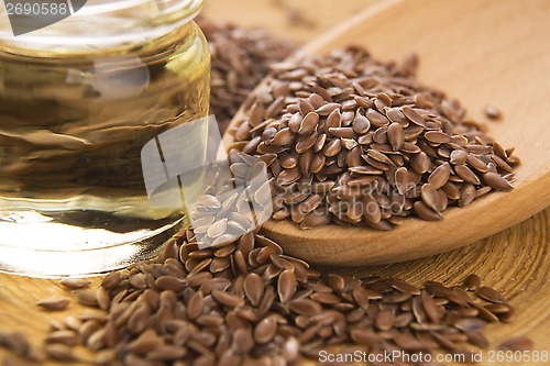 Image of Linseed oil and flax seeds on wooden background 