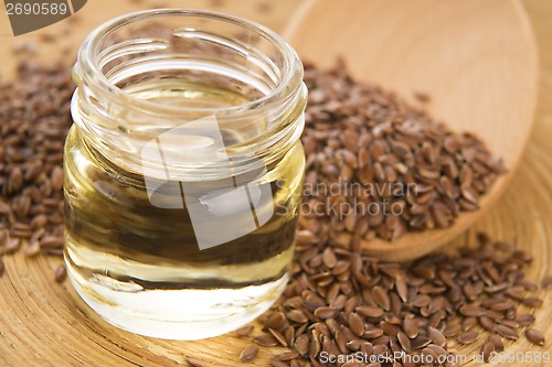 Image of Linseed oil and flax seeds on wooden background 