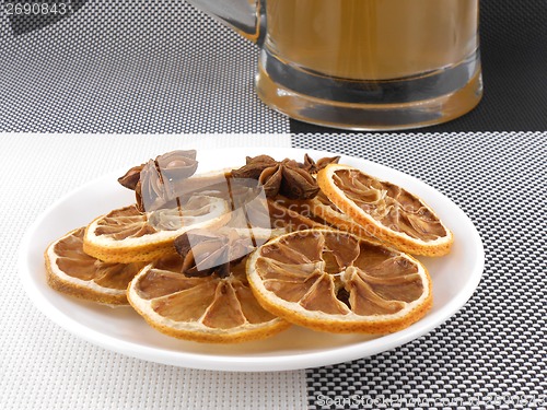 Image of beer mug with cinnamon and lemon on white plate