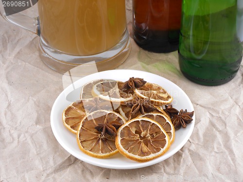 Image of beer bottle with cinnamon and lemon on white plate