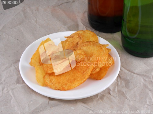 Image of Beer bottle and potato chips on white plate