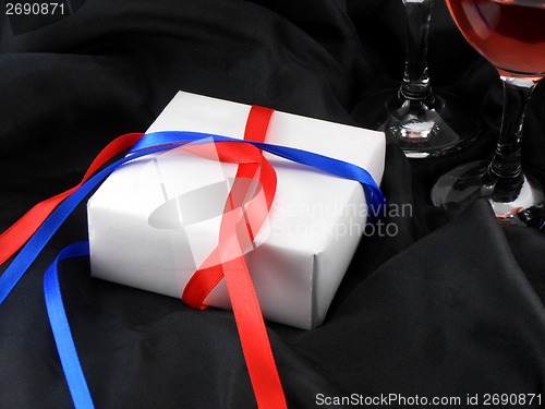 Image of wine glass cup and white present on black background