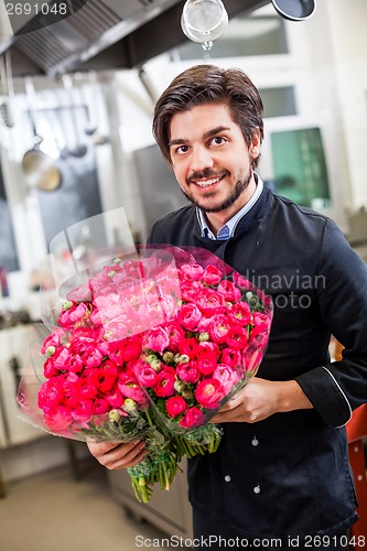 Image of Smiling chef holding bunches of fresh flowers