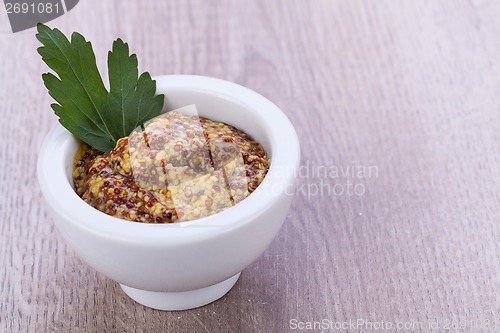 Image of fresh yellow mustard in white bowl with parsley decorated