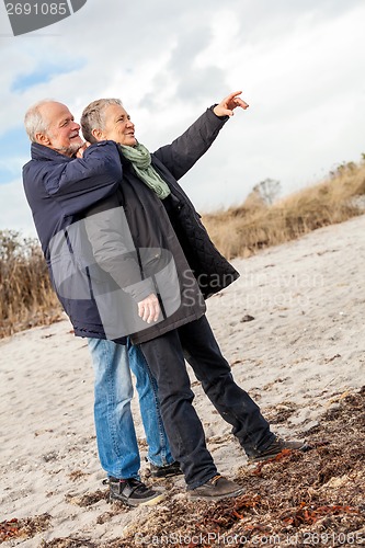 Image of happy elderly senior couple walking on beach