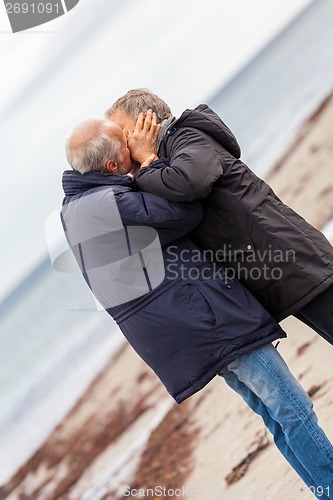 Image of happy elderly senior couple walking on beach