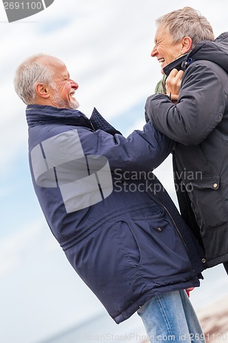 Image of happy elderly senior couple walking on beach