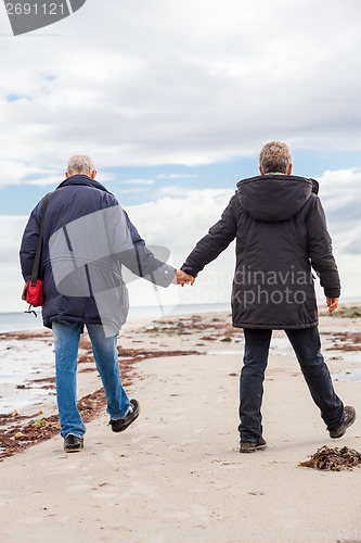 Image of happy elderly senior couple walking on beach