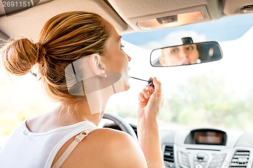 Image of Beautiful woman applying makeup in the car