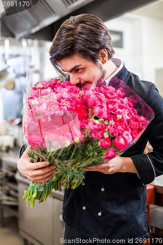 Image of Smiling chef holding bunches of fresh flowers