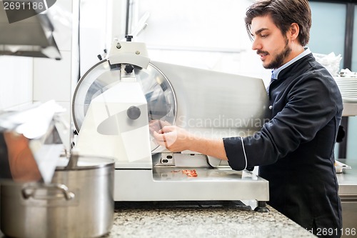 Image of Commercial cook or chef slicing cold meat