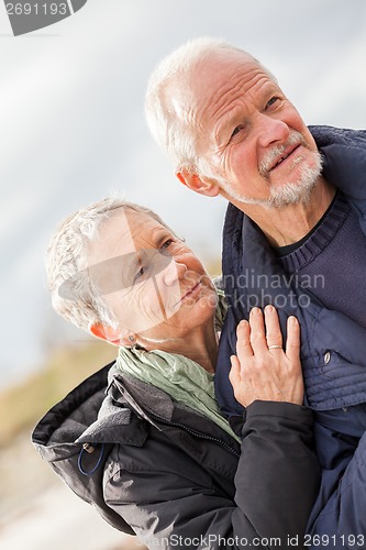 Image of happy elderly senior couple walking on beach