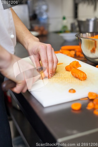 Image of Chef in uniform preparing fresh carrot batons