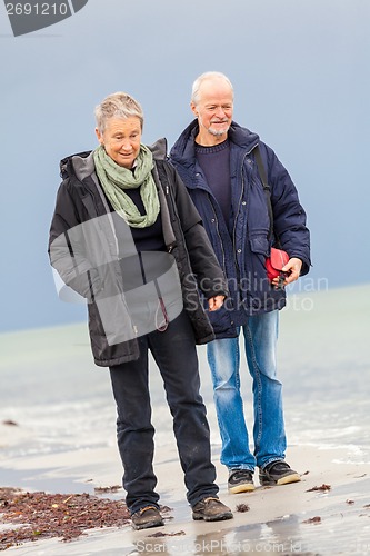 Image of happy elderly senior couple walking on beach