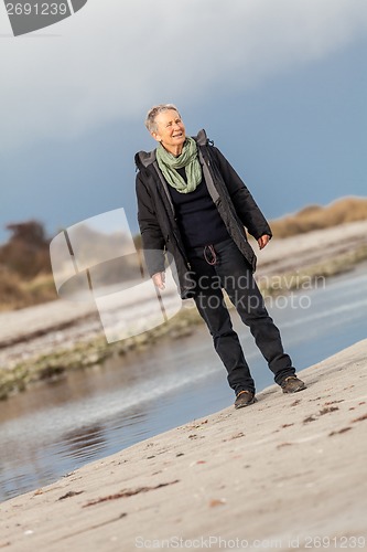 Image of Happy senior woman frolicking on the beach