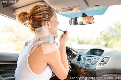 Image of Beautiful woman applying makeup in the car