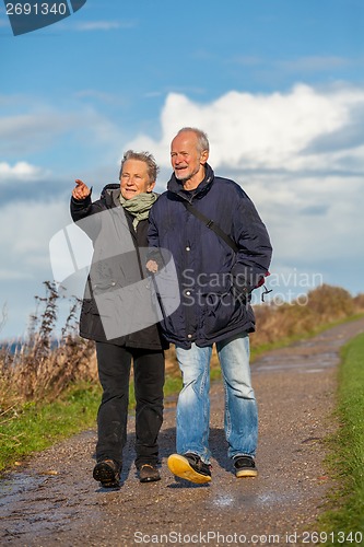 Image of happy elderly senior couple walking on beach