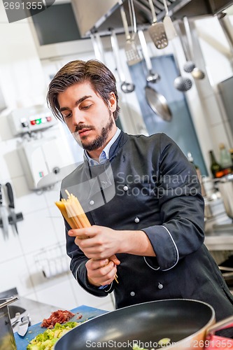 Image of Attractive friendly chef preparing spaghetti