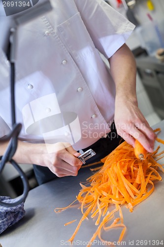 Image of Chef in uniform preparing fresh carrot batons