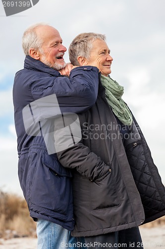 Image of happy elderly senior couple walking on beach