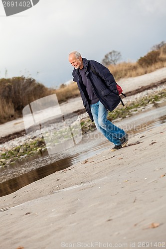 Image of Elderly energetic man running along a beach