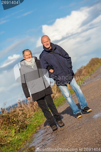 Image of happy elderly senior couple walking on beach