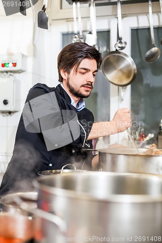 Image of Chef stirring a huge pot of stew or casserole