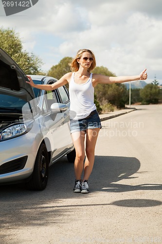 Image of attractive young woman thumbing a lift