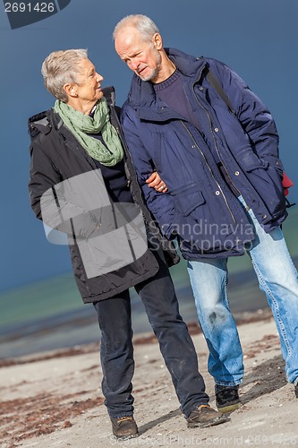 Image of happy elderly senior couple walking on beach