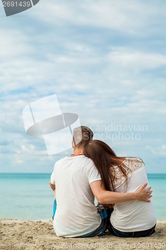 Image of romantic young couple sitting on the beach in summer