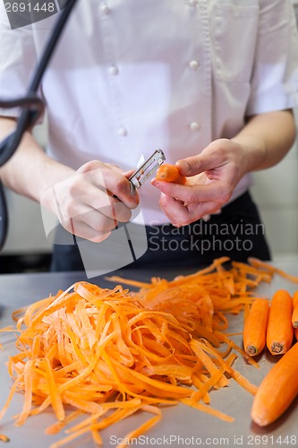 Image of Chef in uniform preparing fresh carrot batons