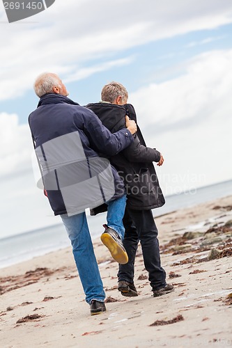 Image of happy elderly senior couple walking on beach