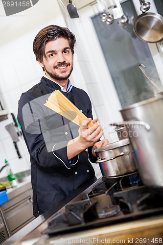 Image of Attractive friendly chef preparing spaghetti