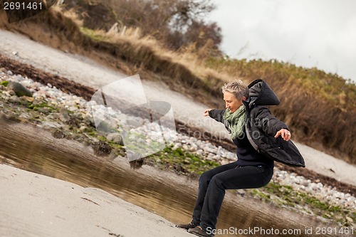 Image of Happy senior woman frolicking on the beach