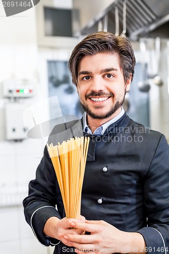 Image of Attractive friendly chef preparing spaghetti