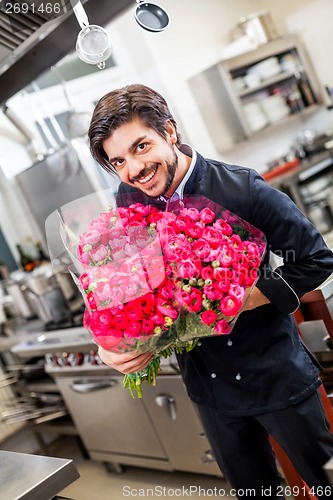 Image of Smiling chef holding bunches of fresh flowers