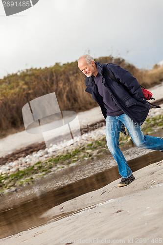 Image of Elderly energetic man running along a beach