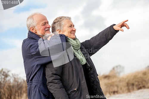 Image of happy elderly senior couple walking on beach