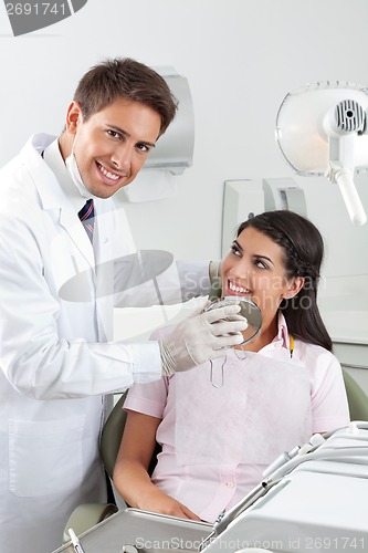 Image of Male Dentist Showing Result Of His Work To Patient