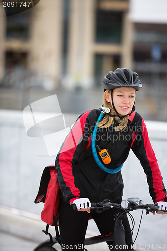 Image of Young Woman Riding Bicycle With Courier Delivery Bag