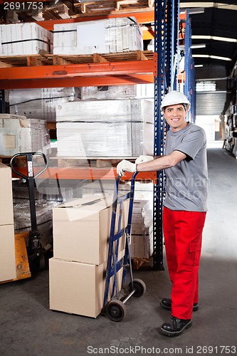 Image of Warehouse Worker With Handtruck Loading Cardboard Boxes